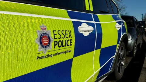 A close up of the side of a blue and yellow police car, with Essex Police emblem on the side of the door. 