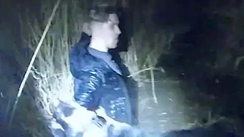Man standing in a swamp with water up to his waist at night.
