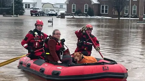 Handout photo from Clarksville Fire Rescue shows recue workers rowing a boat carrying a woman and dog