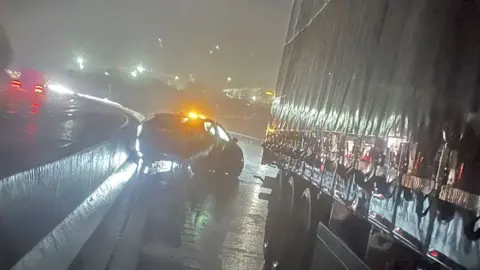 Lancashire Police A night-time scene of the crash showing a car by the central reservation and the back part of a lorry by the side of it