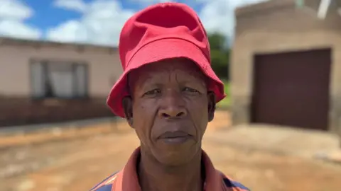 A man in a red hat looks into the camera.