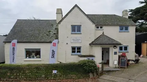 Google A whitewashed two-storey building has pop up signs saying 'Leach Pottery' and 'shop' and a sign on the property itself saying 'The Leach Pottery'.