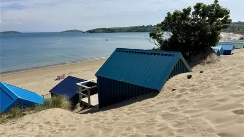 Beresford Adams Bathing huts overlooking sandy beach and a calm sea