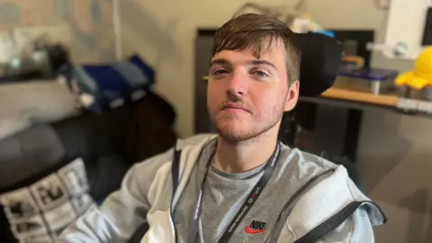 Seth Marks faces the camera wearing a grey jacket and T-shirt.