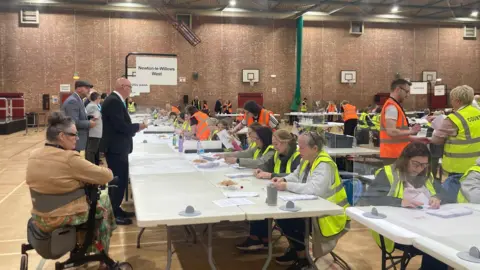 Women and men in high vis count ballot papers