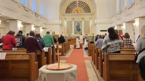 Madeleine Resühr Pictured here is the church in the modern day. This colourful photograph from the back of the church is facing the alter with a copy of Raphael's Sistine Madonna at its centre. The congregation is stood, facing the alter, engaged in worship as clergymen lead at the front. 