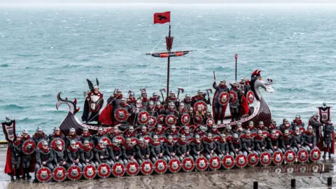 PA Media Members of the Jarl Squad line up on the long boat at the harbour in Lerwick