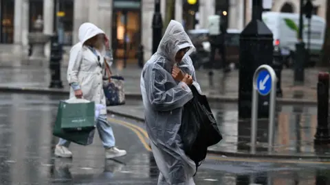 People walk along a street in the rain