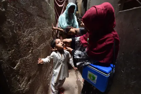 Shahzaib/EPA-EFE A health worker administers polio vaccine drops to a child 