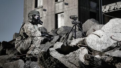 Image of a soldier in a war zone wearing a gas mask