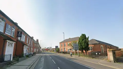 Blue sky above on a road with red brick properties either side