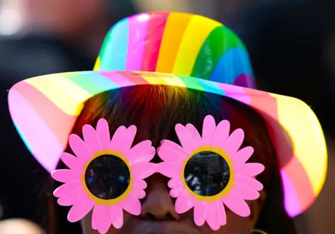 Esa Alexander / Reuters Women wears a rainbow hat and pink sunglasses.