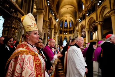 Jordan Pettitt / PA Media Members of the clergy stand and wait inside the cathedral
