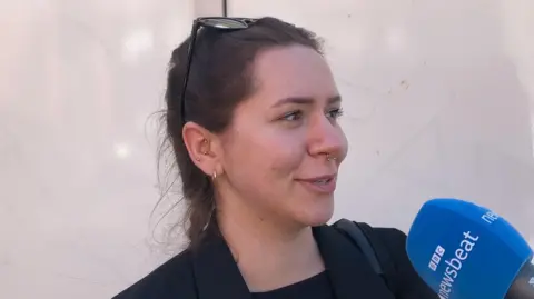 Woman with hair in a braid seaking to BBC Newsbeat mic