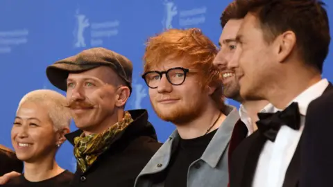 Getty Images/Dominique Charriau/WireImage BERLIN, GERMANY - FEBRUARY 23: (L-R) Kimmie Kim, Foy Vance, Ed Sheeran, Murray Cummings and Alejandro Reyes-Knight pose at the 'Songwriter' photo call during the 68th Berlinale International Film Festival Berlin at Grand Hyatt Hotel on February 23, 2018 in Berlin, Germany. (Photo by Dominique Charriau/WireImage)