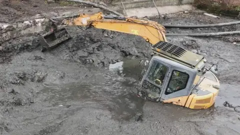 A digger stuck in a pond