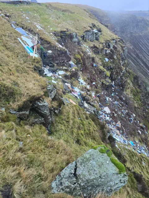 Nathan Dixon Another view of the fly tipped waste down the side of the mountain - this time looking across with the rest of the mountain ridge in the background. 