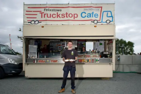 Lewis Elder standing in front of the Truckstop Cafe van at Felixstowe Truckstop