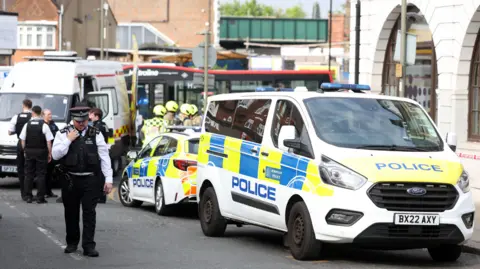 Getty Images Police and ambulance cars parked on the street with the Natwest bank on the righthand side. 