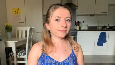 BBC Abbi Brown, a young blonde woman wearing a patterned blue sleeveless top