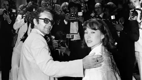 Getty Images Jean-Luc Godard accompanied by French actress Nathalie Baye pose for the presentation of his film "Sauve qui peut (la vie)", on May 22, 1980