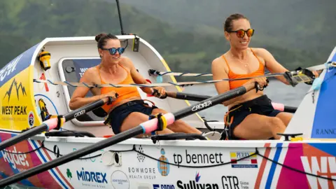 Team Wild Waves Jessica Oliver and Charlotte Harris smiling as they row across the finish line in Hawaii