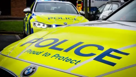 Two police cars side by side. With the words 'police proud to protect' on the bonnet. 