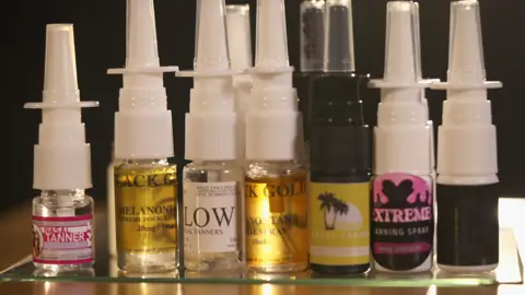 Small bottles of nasal tanners. They have white and black caps and colourful labels.
