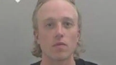 West Mercia Police A police headshot of a man with blond hair who is looking at the camera. 