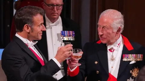 Emmanuel Macron (left) and King Charles clink glasses in a toast