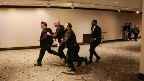 Reuters Mike Johnson is bundled through a room by Secret Service