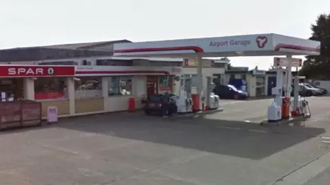 Google A white and red petrol pump canopy that reads Airport Garage is in front of a building, which has a SPAR sign across it.