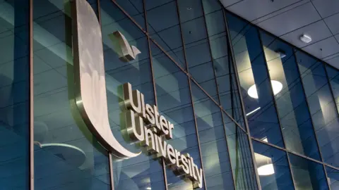 A row of windows with Ulster University written across them in silver. 