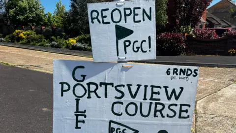 BBC A cardboard sign reading "Portsview Golf Course 6 rounds at least"