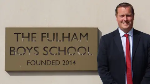  The Fulham Boys School David Smith standing next to The Fulham Boys School sign