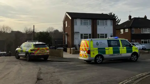 Louise Parry/BBC Two ambulance service vehicles outside a property in a residential street