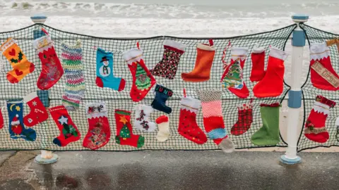 Weymouth Esplanade running alongside the beach with hundreds of festival stockings attached to the seafront railings.