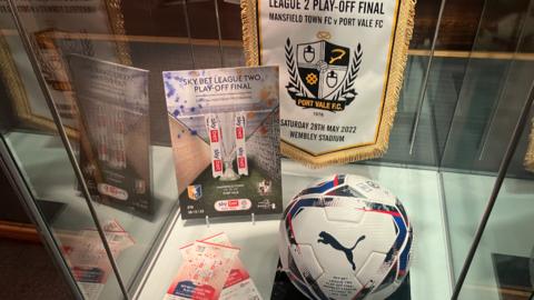 A football, pendant and programme from Port Vale's 2022 League Two play-off final