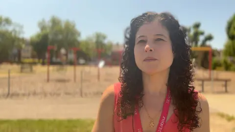 Charlotte Gerada waering a red top, in front of a play park