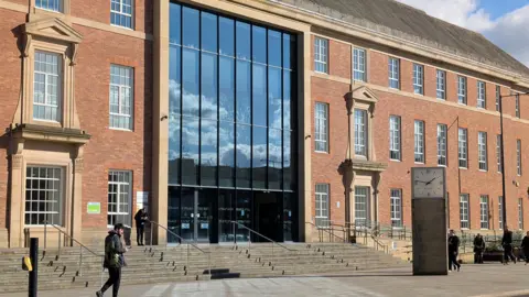 Large orange brick building with rectangular windows 