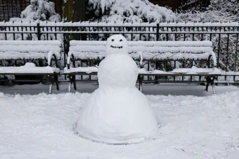 Getty Images Een sneeuwpop staat naast een bankje in het park