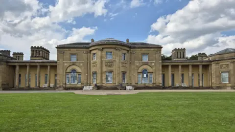 Honey-coloured neoclassical pillars on either side of the front of Heaton Hall. It looks out over a green lawn