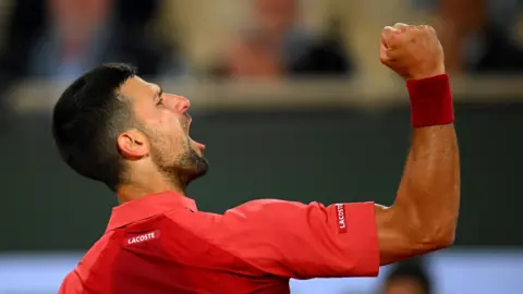 Novak Djokovic waves his fist and roars during his 2024 French Open match against Pierre-Hugues Herbert