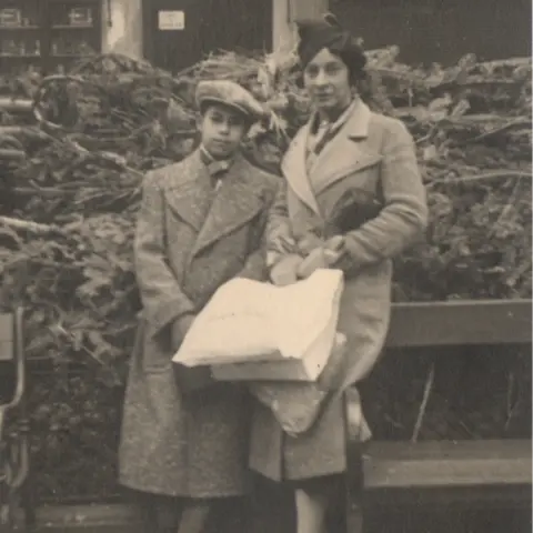 Herbert King Black and white photo of a teenage Herbert King with his mother who is holding a number of carrier bags
