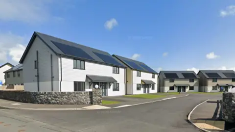 Google A cul-de-sac of semi-detached modern homes lining a road. They all have solar panels on the roof with wooden cladding on the top of the buildings, and each has a grey porch roof. 