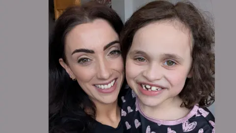 Family handout Faye and Isabelle smiling at the camera. Faye has a dark top while Isabelle is wearing a dark top decorated with pink hearts.