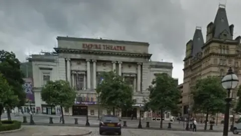 The Empire Theatre, with its name in red letters, by an empty street with just one pedestrian walking past bollards