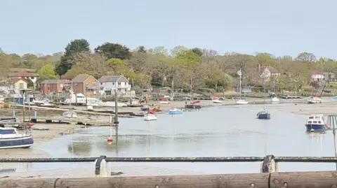 BBC Weather Watcher Kay Wootton Bridge, Isle of Wight - shoreline with boats at low tide sat on the sand