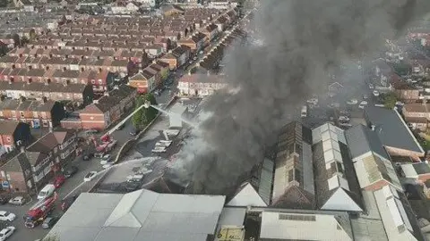 GMFRS An aerial view of the black smoke billowing out into the sky from above an industrial unit in 