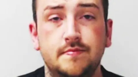 Police mugshot of Peter Garland, a man with stubble, looking at the camera.